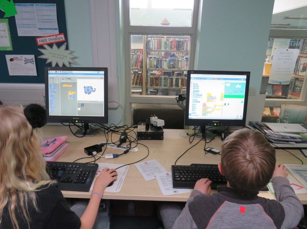 A photo of two young people learning to code games in Scratch