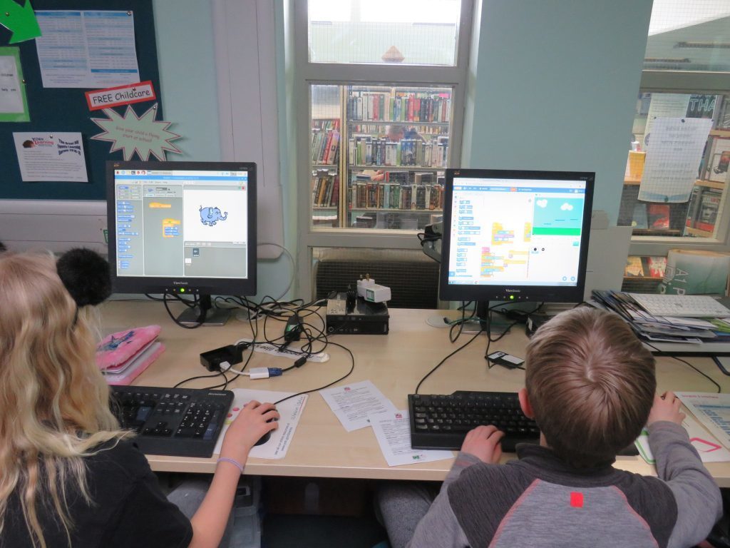 Two young people learning to code games in Scratch
